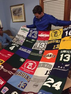 a man is holding up a quilt made to look like baseball jerseys