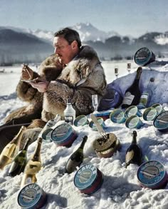 a man sitting in the snow with lots of beer bottles