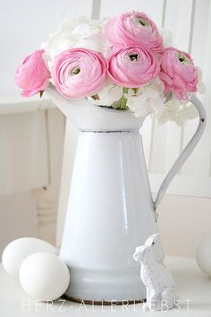 a white pitcher with pink and white flowers in it