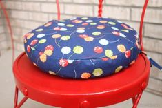 a blue cushion sitting on top of a red chair next to a brick wall,