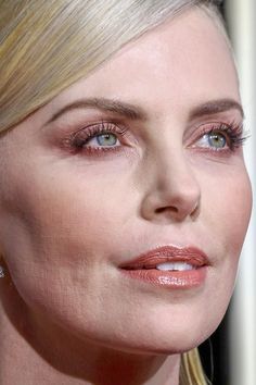 a close up of a woman with blonde hair and blue eyeshadow wearing earrings