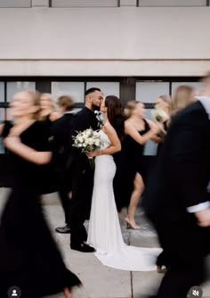 a bride and groom kissing in front of a group of people on their wedding day