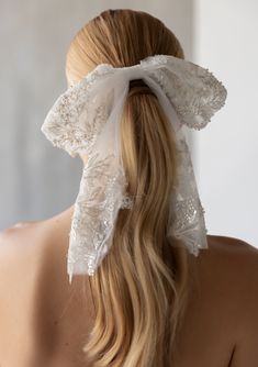 the back of a woman's head wearing a white hair bow with lace on it