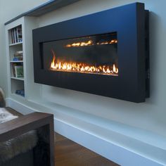 a wall mounted fireplace in a living room next to a book shelf with books on it