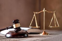 a wooden judge's scale next to an open book and a gavel on a table