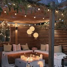 an outdoor seating area with candles and lights on the ceiling, surrounded by wood slats