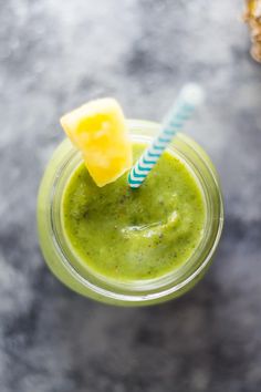 a green smoothie with a blue and white striped straw