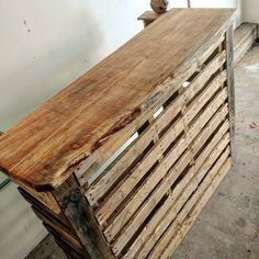 a wooden bench made out of pallets in a room with white walls and concrete flooring