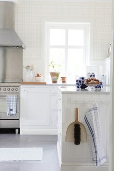 a kitchen with white cabinets and stainless steel stove top oven, dish towel hanging on the wall