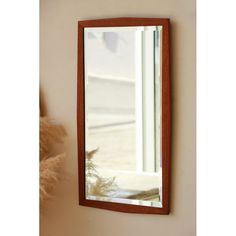 a mirror hanging on the side of a wall next to a vase with flowers in it