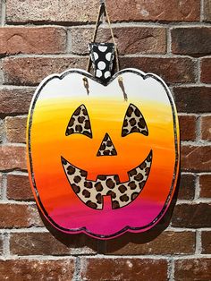 a painted pumpkin hanging on a brick wall with a polka dot bow and leopard print