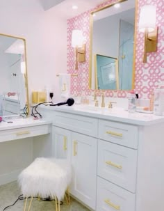 a bathroom with pink and gold wallpaper, white countertops, and vanity area