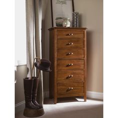 a tall wooden dresser sitting next to a window with a hat on top of it