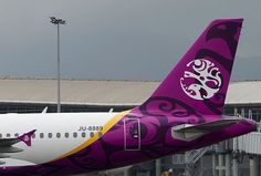 an airplane painted in purple and yellow with designs on it's side at an airport