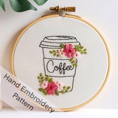 a coffee cup with pink flowers on it and the word coffee is embroidered in white