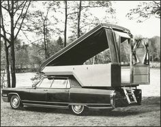 an old black and white photo of a car with a camper attached to it