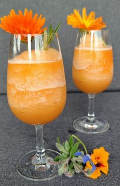 two glasses filled with orange liquid and flowers