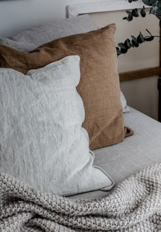 a bed with two pillows on top of it and a plant in the corner next to it