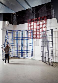 a woman is standing in front of an art installation with blue and red scaffolding