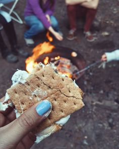 a person holding a cracker over an open fire pit