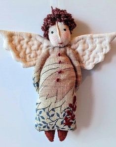 an angel ornament hanging on a wall with red hair and blue eyes is made from fabric