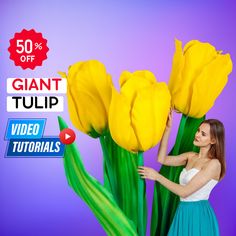 a woman in a blue dress standing next to yellow flowers with the words giant tulip on it