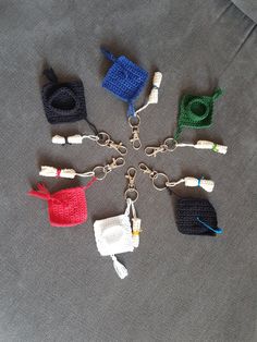 six crocheted purses are arranged in a circle on a gray surface, with one keychain hanging from the middle