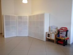 an empty room with white walls and wooden toys on the floor in front of it