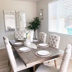 the dining room table is set with white plates and place settings