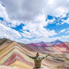 a man standing on top of a mountain with his arms wide open