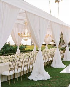 an outdoor wedding setup with white draping and chandeliers