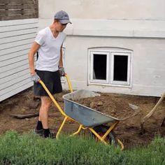 a man is pushing a wheelbarrow in the yard