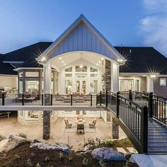 a large house that has a deck and patio in front of it with lights on