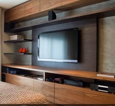 a flat screen tv mounted to the side of a wooden entertainment center in a bedroom