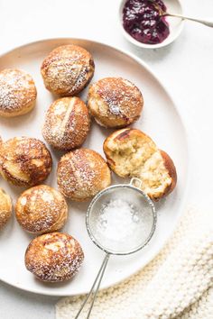 a white plate topped with pastries next to a bowl of jam and a napkin