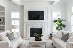 a living room with white furniture and a fireplace