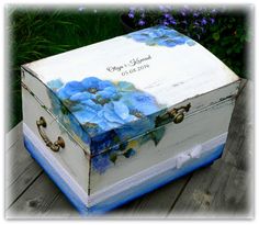 a white box with blue flowers painted on it sitting on top of a wooden table