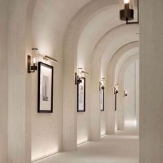 the hallway is lined with arches and framed pictures on the wall, along with floor to ceiling lighting