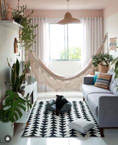 a living room with a hammock hanging from the ceiling and potted plants