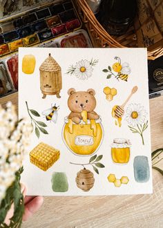 a hand holding up a card with bees and honey on it, surrounded by flowers