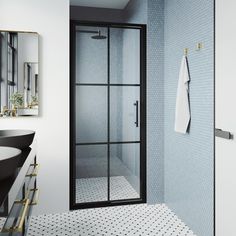 a bathroom with a glass shower door and black counter top, along with a white rug on the floor