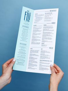 two hands holding up a blue and white brochure in front of a blue background