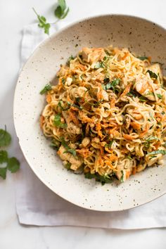 a bowl filled with noodles and vegetables on top of a white napkin next to a fork