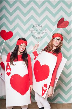 two women dressed in costumes holding up signs with hearts on them and one wearing glasses