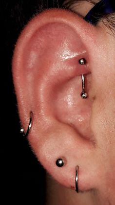 an ear with three piercings attached to it's middle part and two smaller ones behind the ear