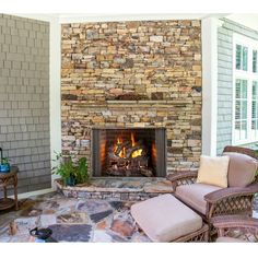 a stone fireplace with two wicker chairs next to it