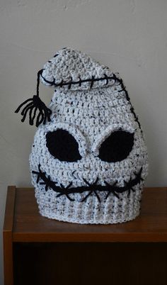 a crocheted skull hat sitting on top of a wooden table next to a white wall