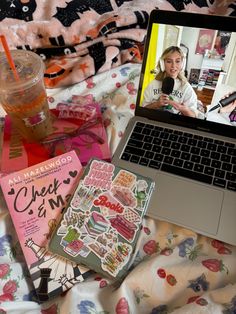 an open laptop computer sitting on top of a bed next to a book and drink