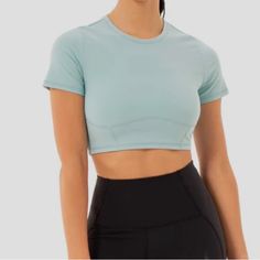 a woman wearing a blue crop top and black skirt with her hands in her pockets