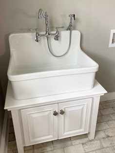 a white sink sitting under a faucet next to a wall mounted light fixture